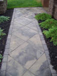 Beautiful paver walkway and entry with landscaping on sides